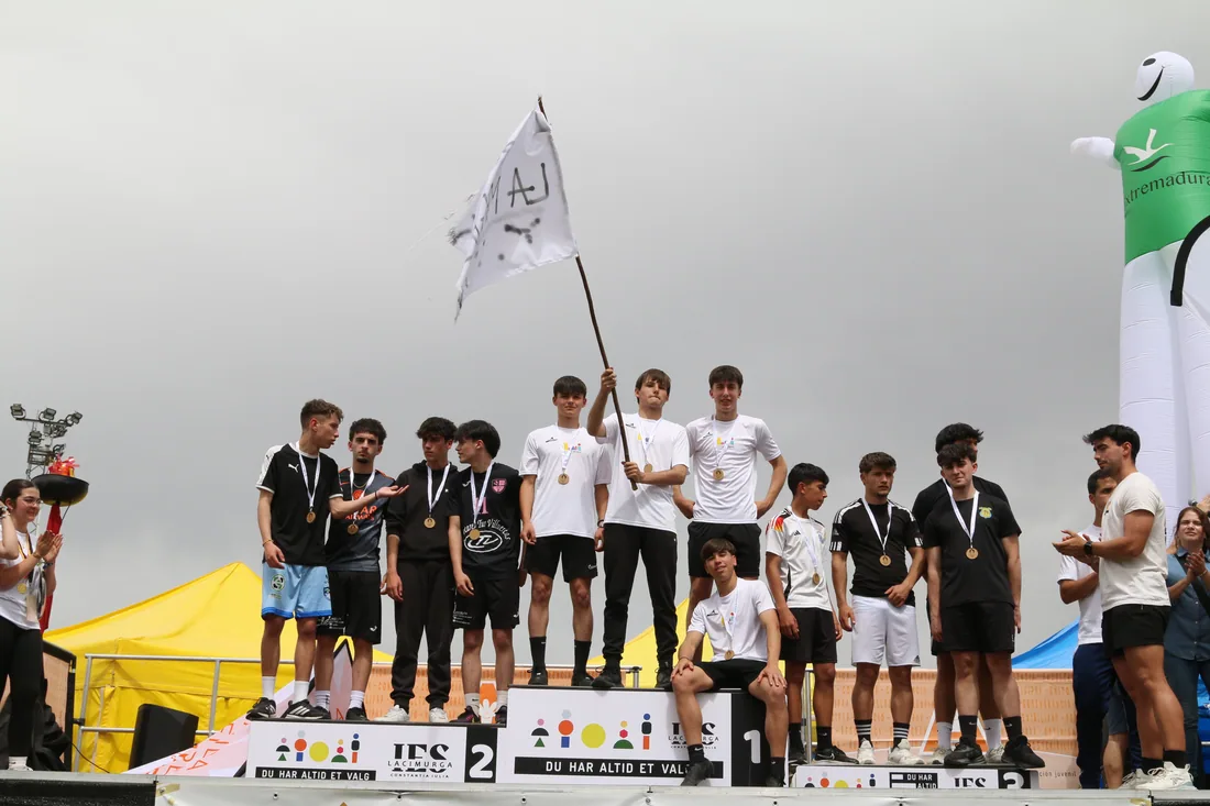 Un equipo celebra en el podio con las banderas al fondo